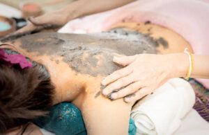 woman getting a clay mask rubbed on her back