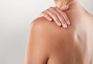 Closeup studio shot of a woman touching her shoulder