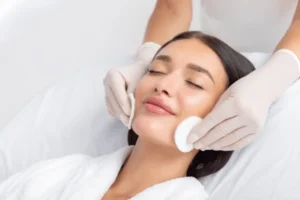 woman getting her face rubbed with two cotton rounds